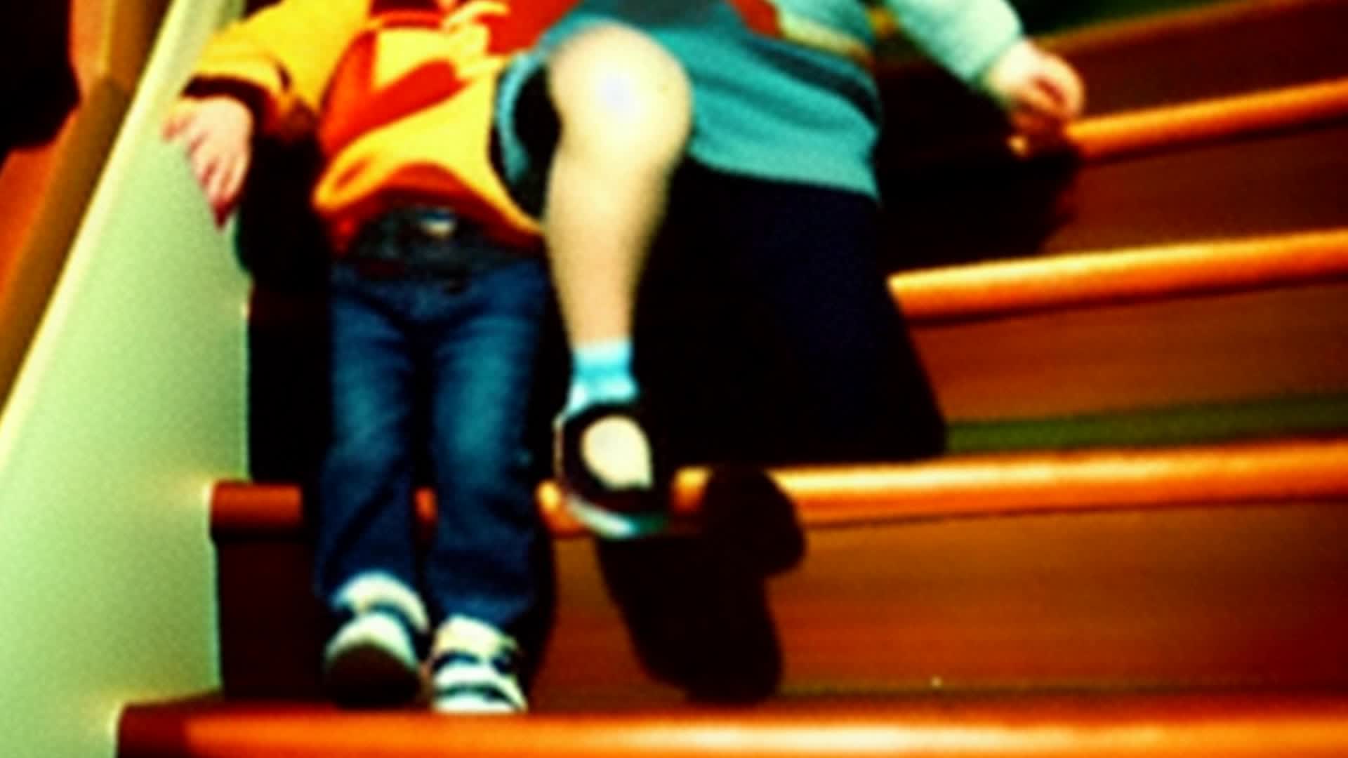 a little brunette girl and 2 brunette toddler boys on the staircase