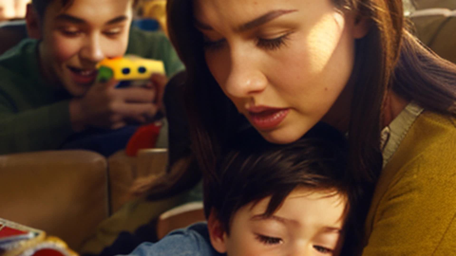 Two little brunette boys one little brunette girl fighting with blonde mother brunette father Close up Cozy living room full of colorful toys books family photos on the walls sun pouring through large windows