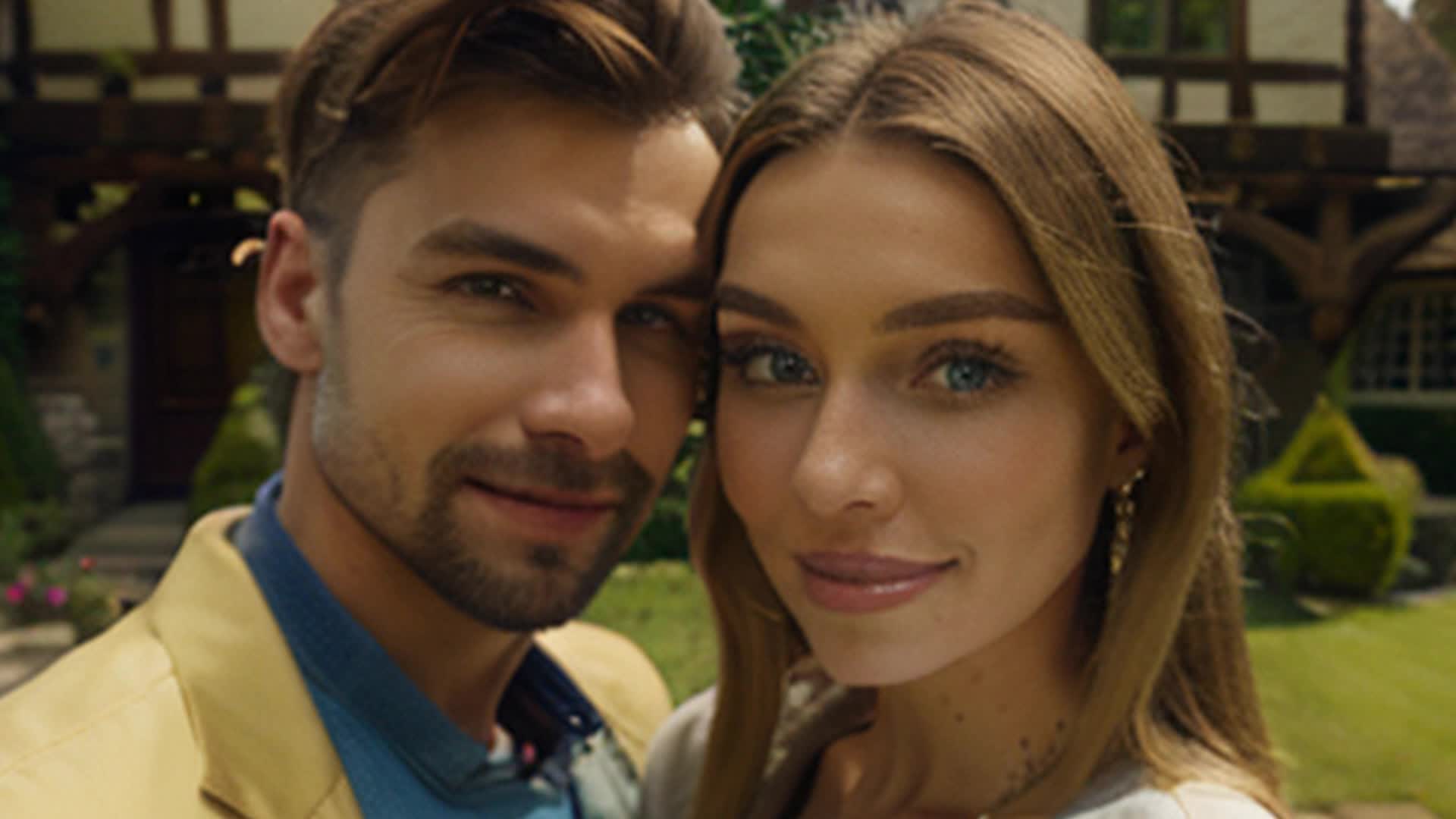 modern happy blonde woman and brunette man posing in front of an English tudor style house