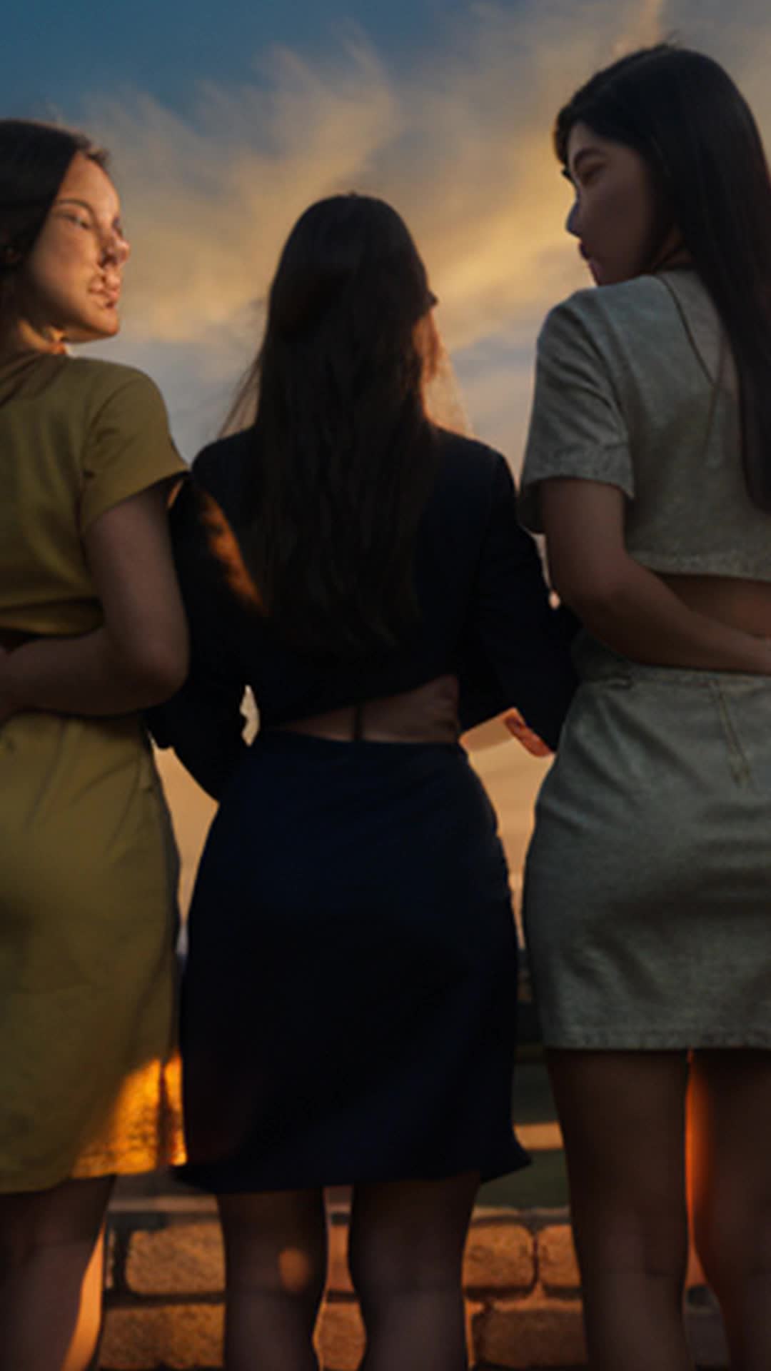 Three determined women lay first brick wide angle peaceful suburban sunrise with vivid sky colors