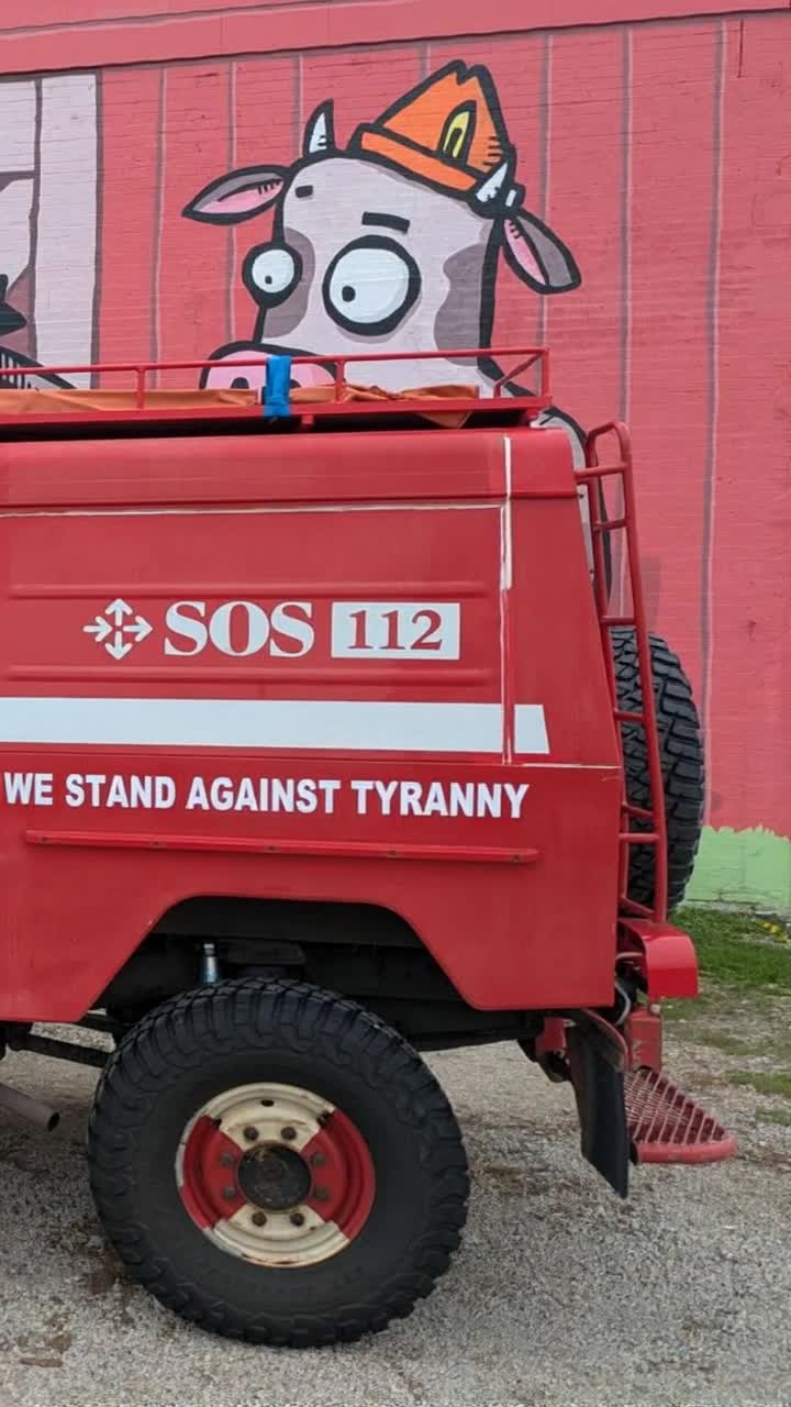 A cartoon cow hides behind a red van but gets discovered by a green alien