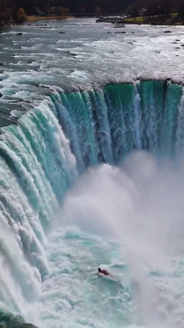 firstperson view of a mischievous daredevil swimming on Niagara Falls and drifting down the waterfall, the water current pulls the daredevil over Niagara Falls and he lands in the waterfall wake at the bottom, RAW, HDR, 8K