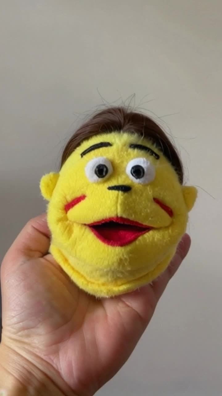 A hand puppet has a cartoonish face drawn on it, toy theater background The face on the handis almost cosmetically pleasing and its a hand puppet, making a surprised face  The hand puppet looks around but where does a hand puppet have to be