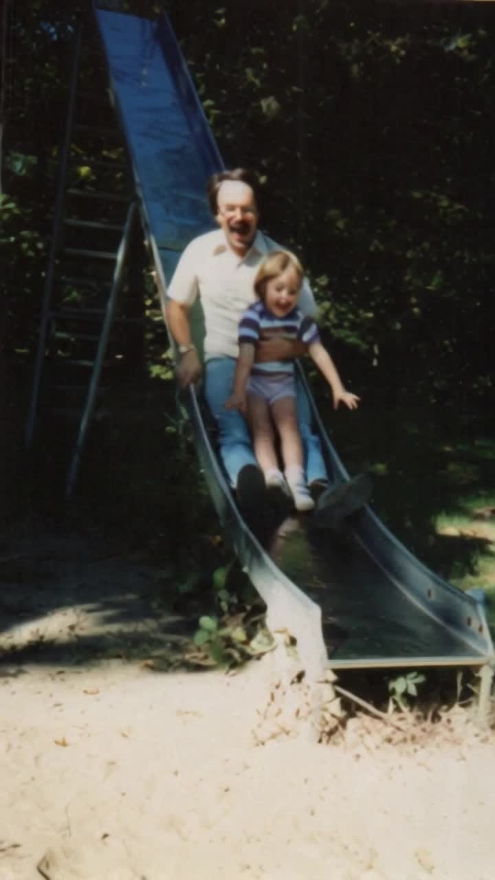 Happy father and daughter go down the slide laughing 