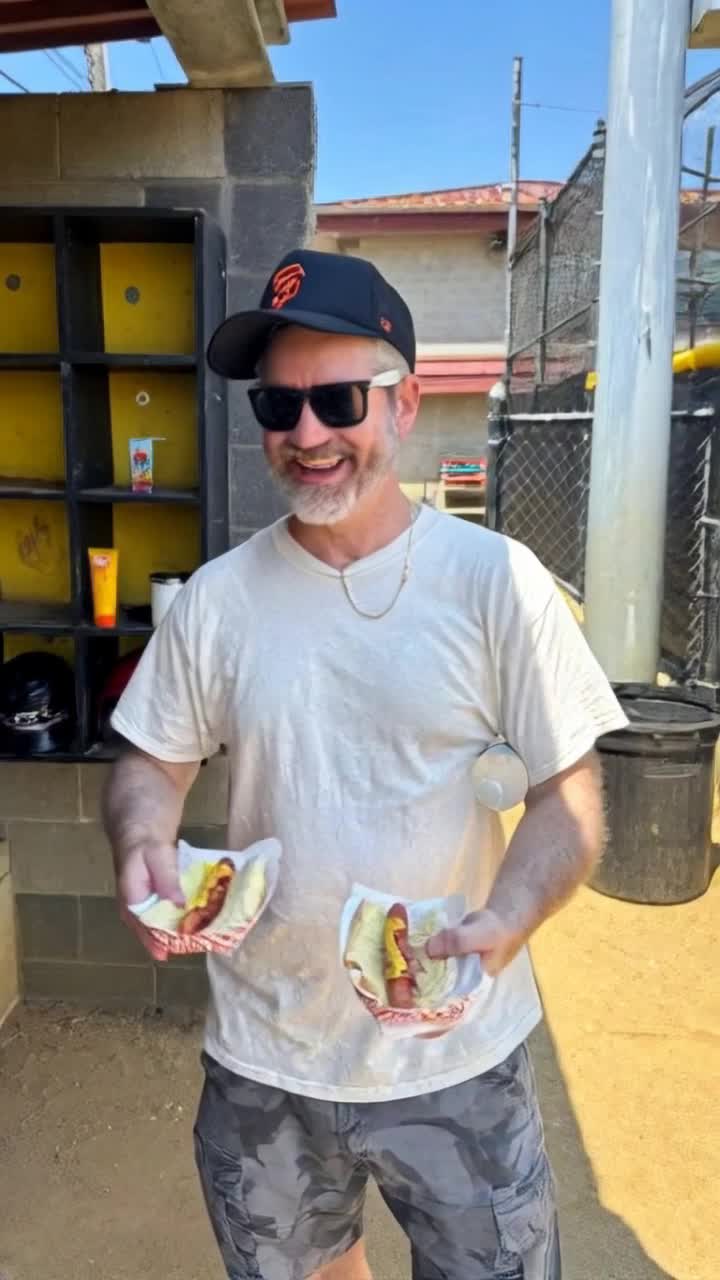 Guy throws the hotdogs away and pulls put money and a cell phone