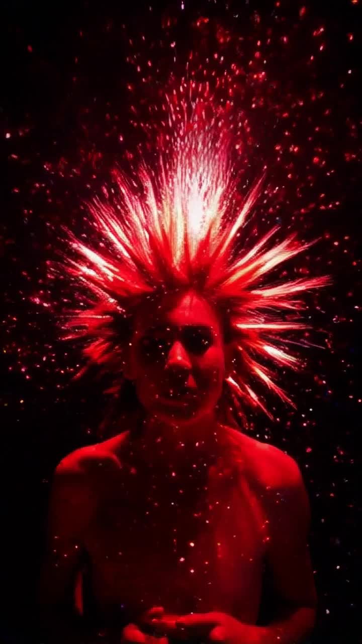 Vibrant energy bands spiral outward in explosive arcs creating vivid iridescence around spiky-haired figure whose hair glimmers with fiery reflections intense red gel lighting envelops dark surroundings creating an electrifying atmosphere shadows dance with vibrant hues illuminating every corner with dynamic bursts of color sparkling particles swirl through the air adding a sense of motion and excitement as light playfully interacts with the spikes creating a captivating spectacle that draws viewers into this mesmerizing scene
