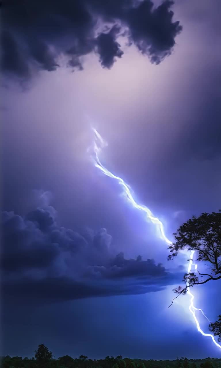 Electric blue lightning bolts dart wildly across a deep velvet sky Midnight clouds twist and twirl menacingly as soft thunder grumbles in the background Each zap of lightning reveals stark silhouettes of swaying trees whispering with the breeze A luminous silver moon emerges shyly from behind tempestuous clouds casting a magical dance of light and shadow Natures aweinspiring performance unfolds showcasing a breathtaking symphony of vibrant illumination and rumbling sound