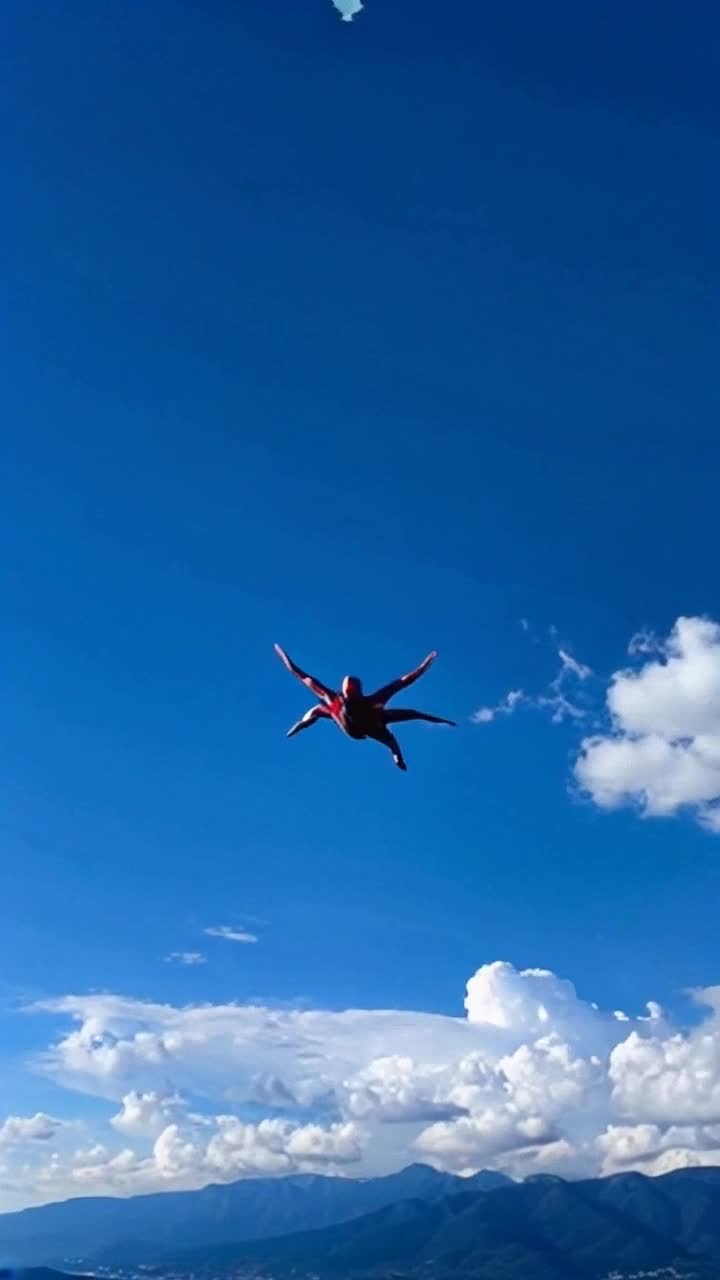 Dramatic superhero soaring through vibrant blue sky with arms outstretched Spirited wind rushing past as colors of sunset streak across horizon Majestic mountains rise in the distance with fluffy clouds drifting lazily around peaks Treelined valley glimmers below highlighting vivid green landscape Alive cityscape buzzes with tiny twinkling lights as day turns to night