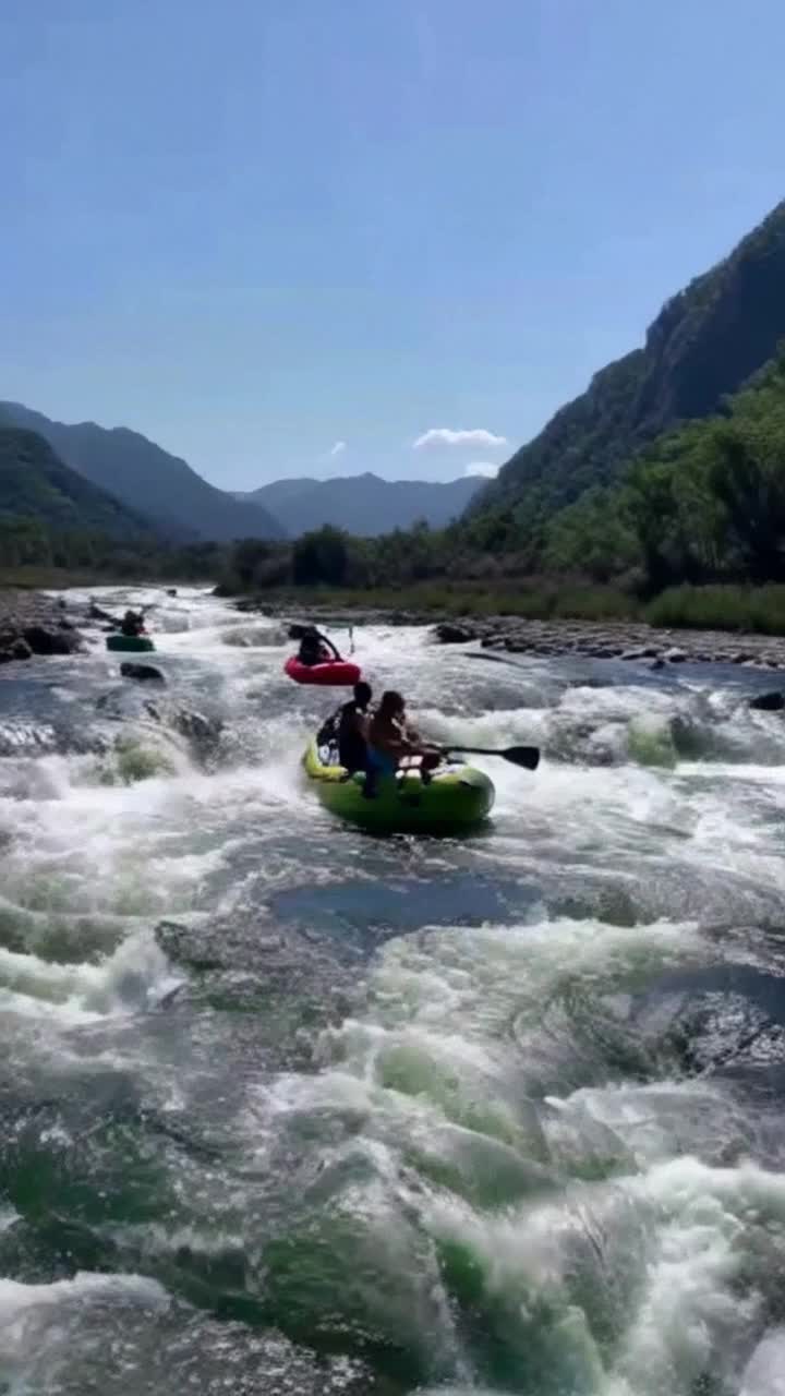 Colorful rafts filled with exhilarated adventurers paddling vigorously through roaring rapids under brilliant azure skies water splashing wildly against vibrant paddles Camera zooming in on joyful faces gasping and laughing as relentless currents surge toward thundering waterfalls Sunlight streaming through lush green canopies showcasing majestic mountains and distant peaks forming a stunning backdrop adorned with swaying wildflowers dancing gracefully in the breeze
