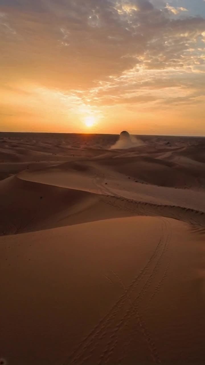 Fierce sand dunes rise majestically under a vibrant sky painted in hues of gold and orange Shimmering waves of heat distorted the horizon as a lone figure wearing rough fabric strides purposefully across the arid landscape Winds whip through the grains creating a mesmerizing dance of sand particles Catching the last rays of sunlight a colossal sandworm emerges from below transforming the scene into a breathtaking spectacle of natures power