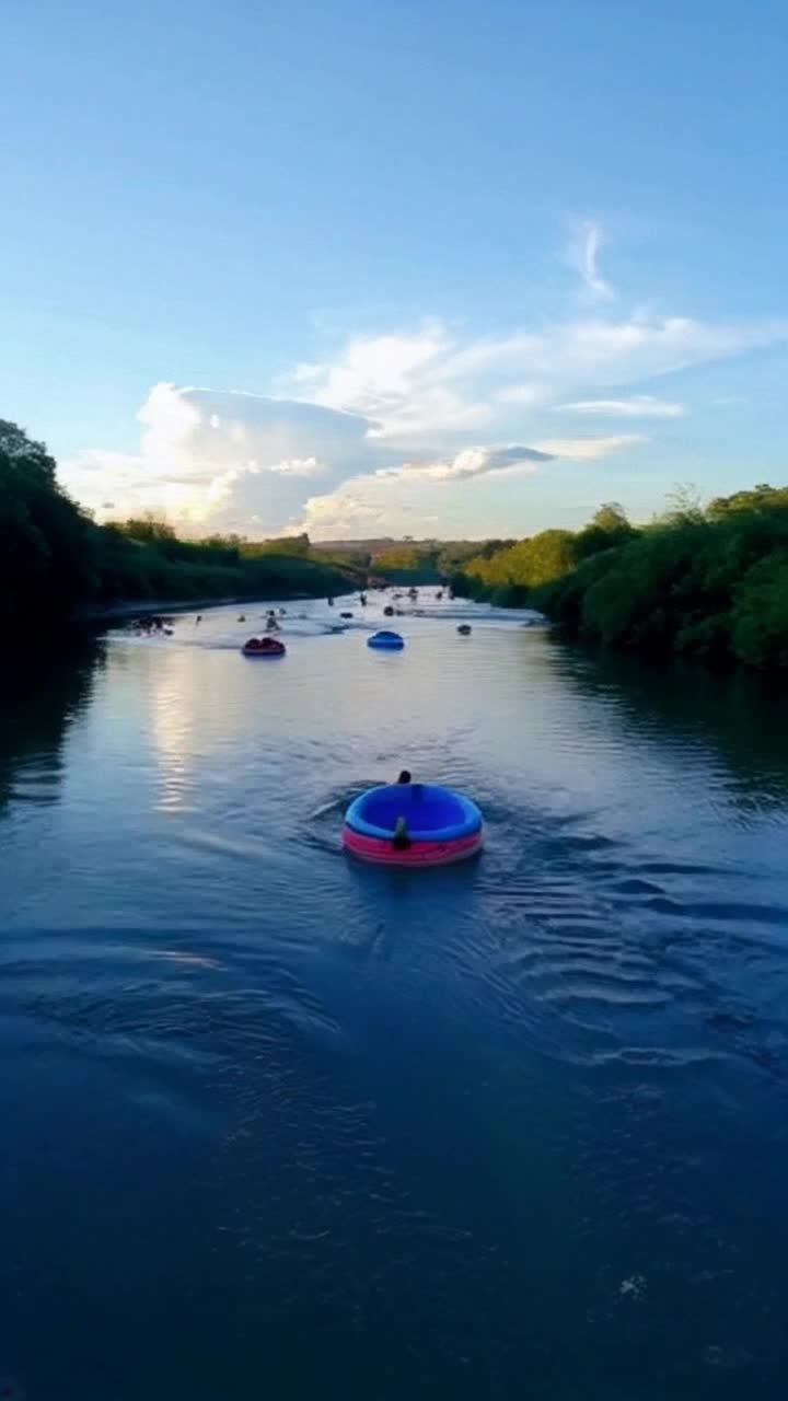 Floating down a river , inner tubes , people and river ,  A popular summer activity for inner peace and relaxation, blue sky with white clouds, mesmerizing morning sunrise, blue river water flowing between greenary and flowers A WATER TUBE, river tubing or inner tubing 