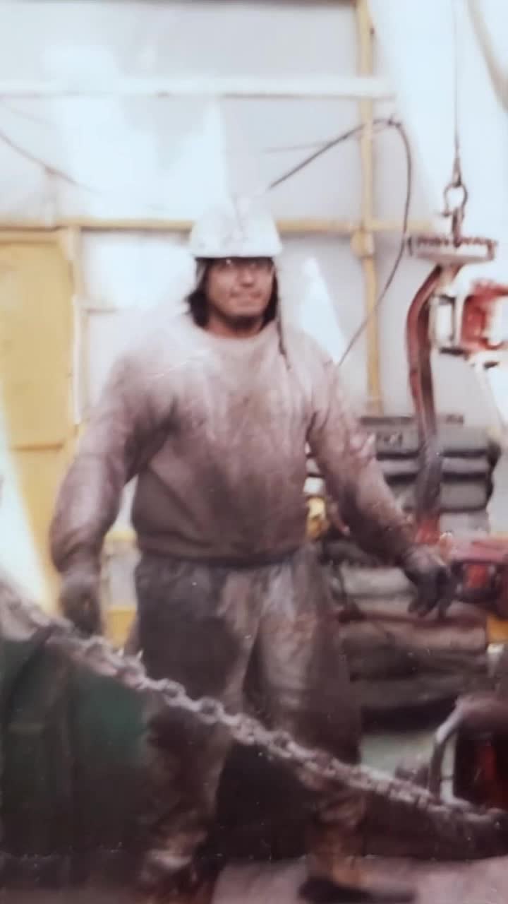 Hardworking father, grinning and moving his head to the tune of heavy rock guitar solo overstanding a vast construction landscape of rural rocky mountains ranges 