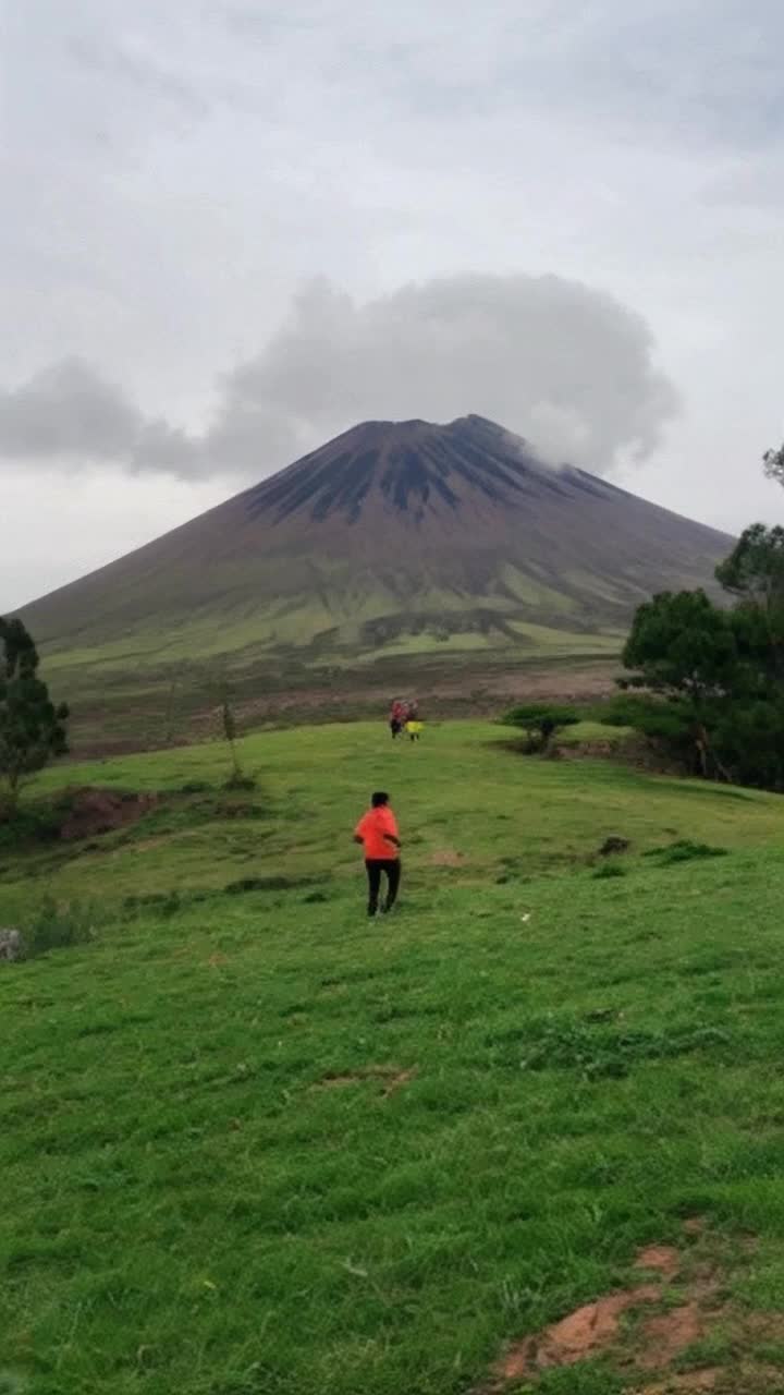 The volcano is dormant but people runs circles around a lush green hill, at worst, an old timer is drinking a glass of bright orange juice