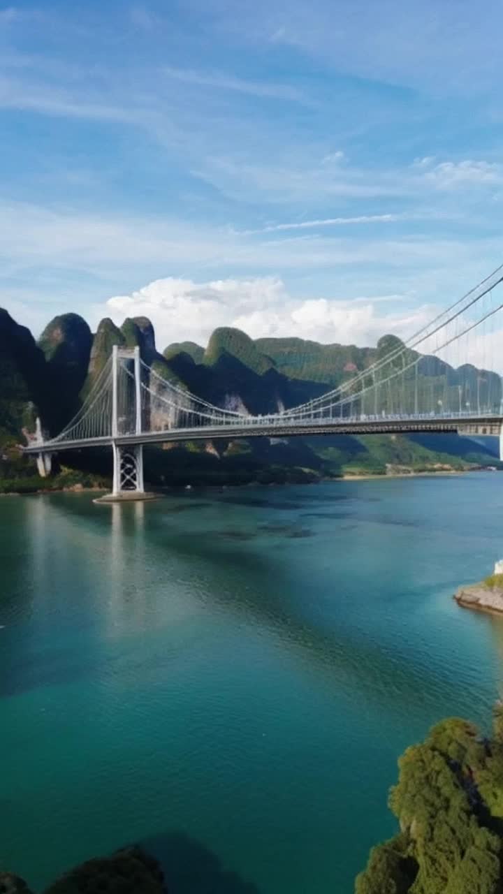 Majestic suspension bridge stretching elegantly for eight miles adorned with intricate carvings and shimmering lights soaring one mile above a sparkling azure river glistening under the sun surrounded by lush green mountains rising majestically in the background wisps of clouds drifting lazily across the sky as birds swoop gracefully below the bridge creating a breathtaking scene of architectural wonder in harmony with natures beauty