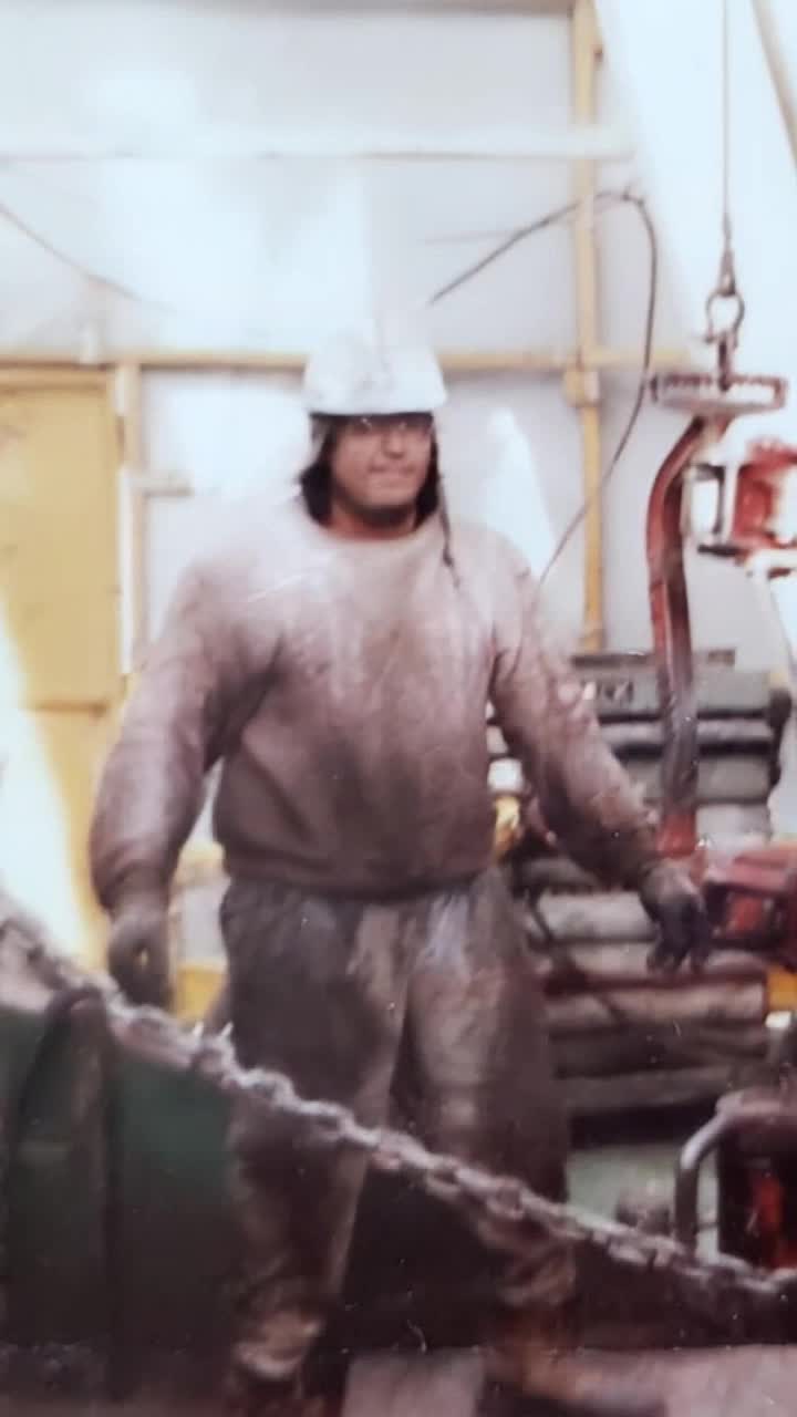 Hardworking father, grinning and moving his head to the tune of heavy rock guitar solo overstanding a vast construction landscape of rural rocky mountains ranges 