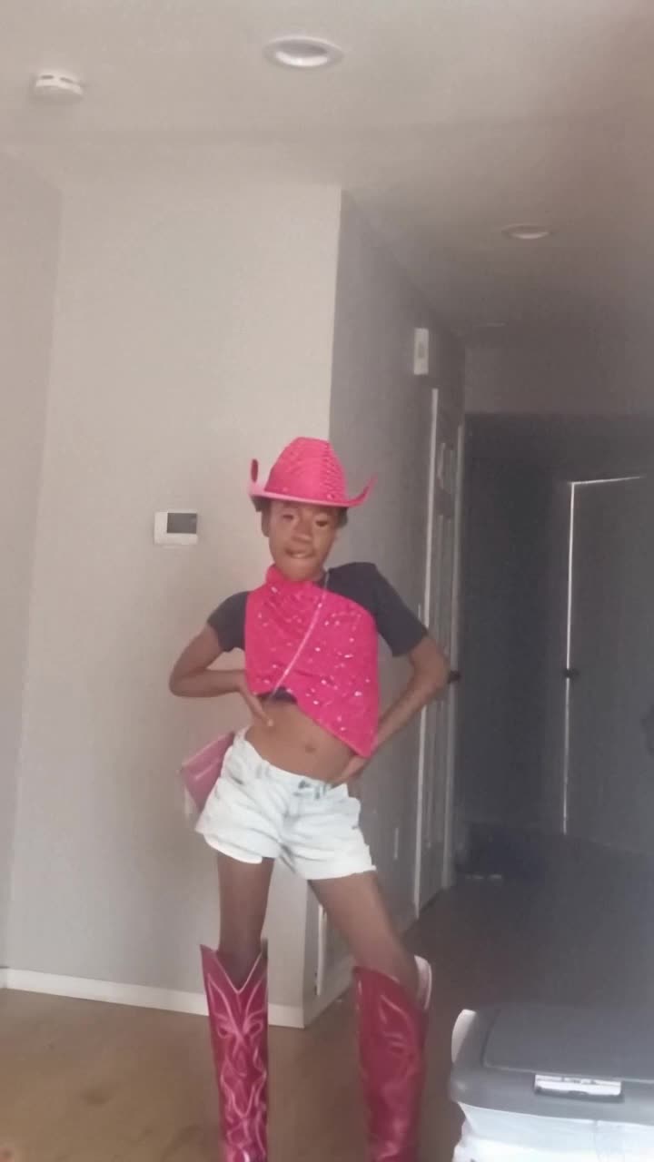 Elegant ebony cowgirl twirling joyfully amidst vibrant city square bustling with energy bright pink shiny cowboy boots glistening in sunlight dazzling smile radiating happiness surrounded by colorful lights reflecting off nearby buildings festive atmosphere inviting laughter and dance infectious rhythm floating through the air creating a celebration of joy and spirit lively crowd mesmerized by her moves capturing the essence of fun and freedom vibrant flowers blooming nearby adding a splash of color to the scene magnifying the excitement of the moment enchanting backdrop of historic architecture framing this lively spectacle