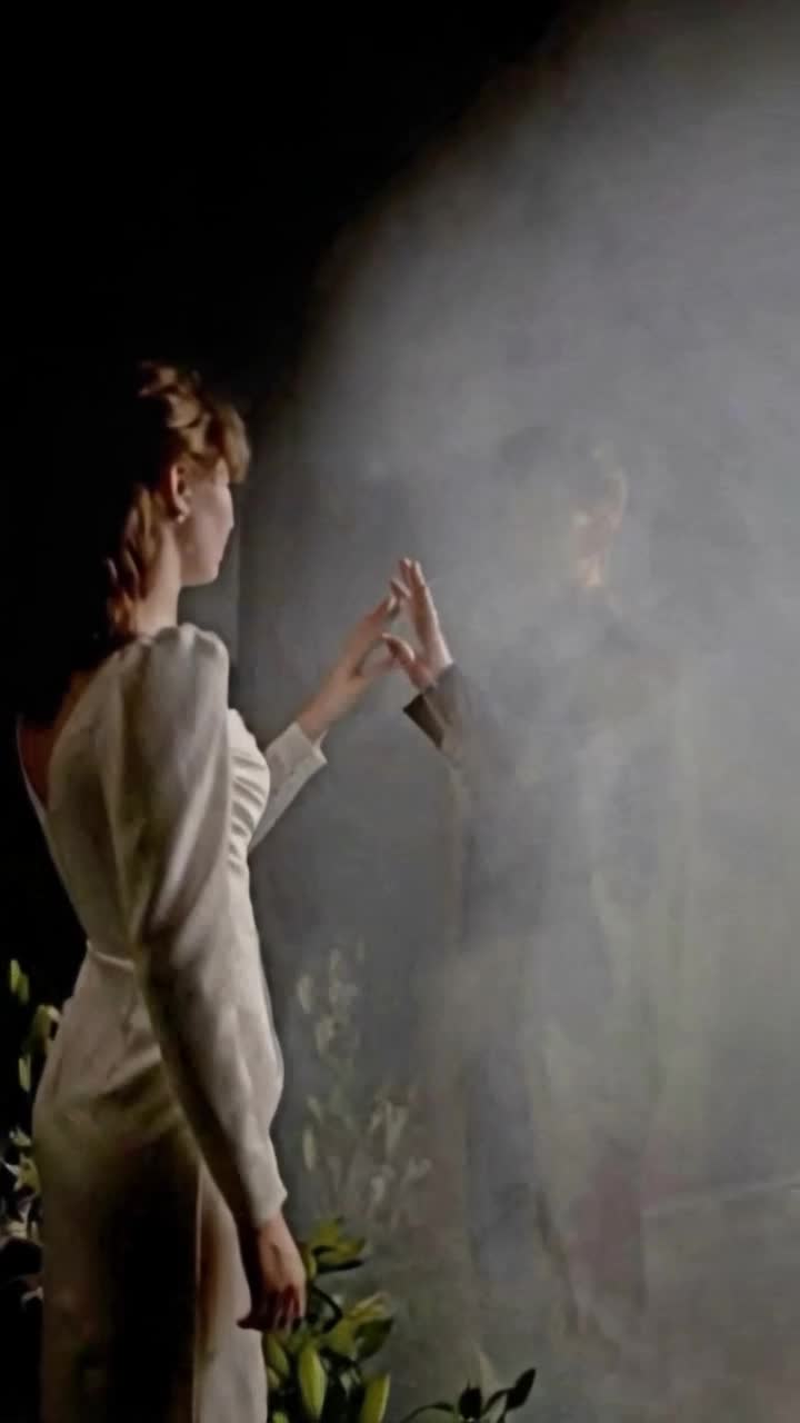 Elegant woman dressed in flowing gown with luminescent fabric extends her delicate hand into swirling mist as shadowy figure reaches out with outstretched fingersurrounded by ethereal fog and soft glimmers of light filtering through creating an atmosphere of mystery and allure whispers of secrets hang in the air as glimpses of silhouettes dance within the haze