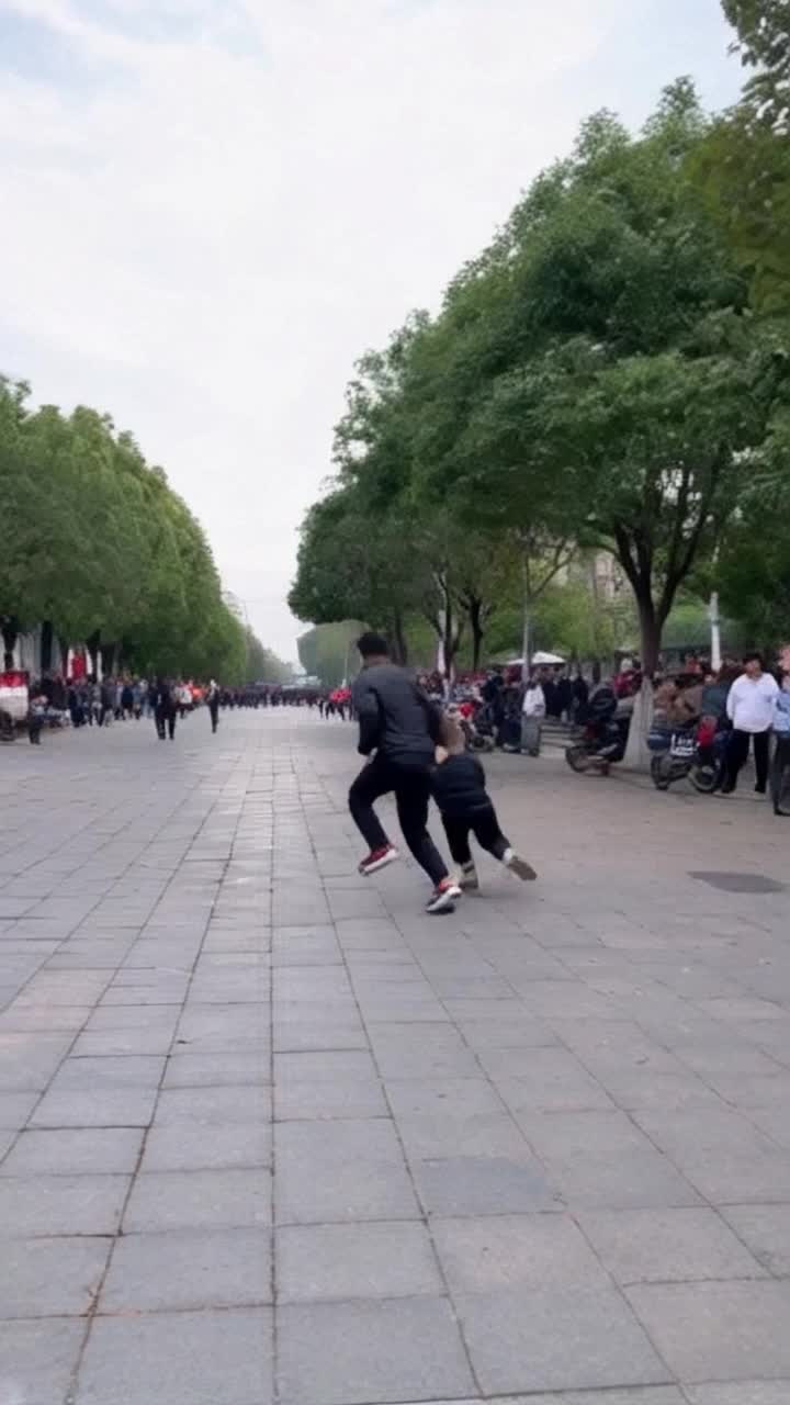 make video man chasing a thief in street running and doing stunts in crowded place around people are watching them
