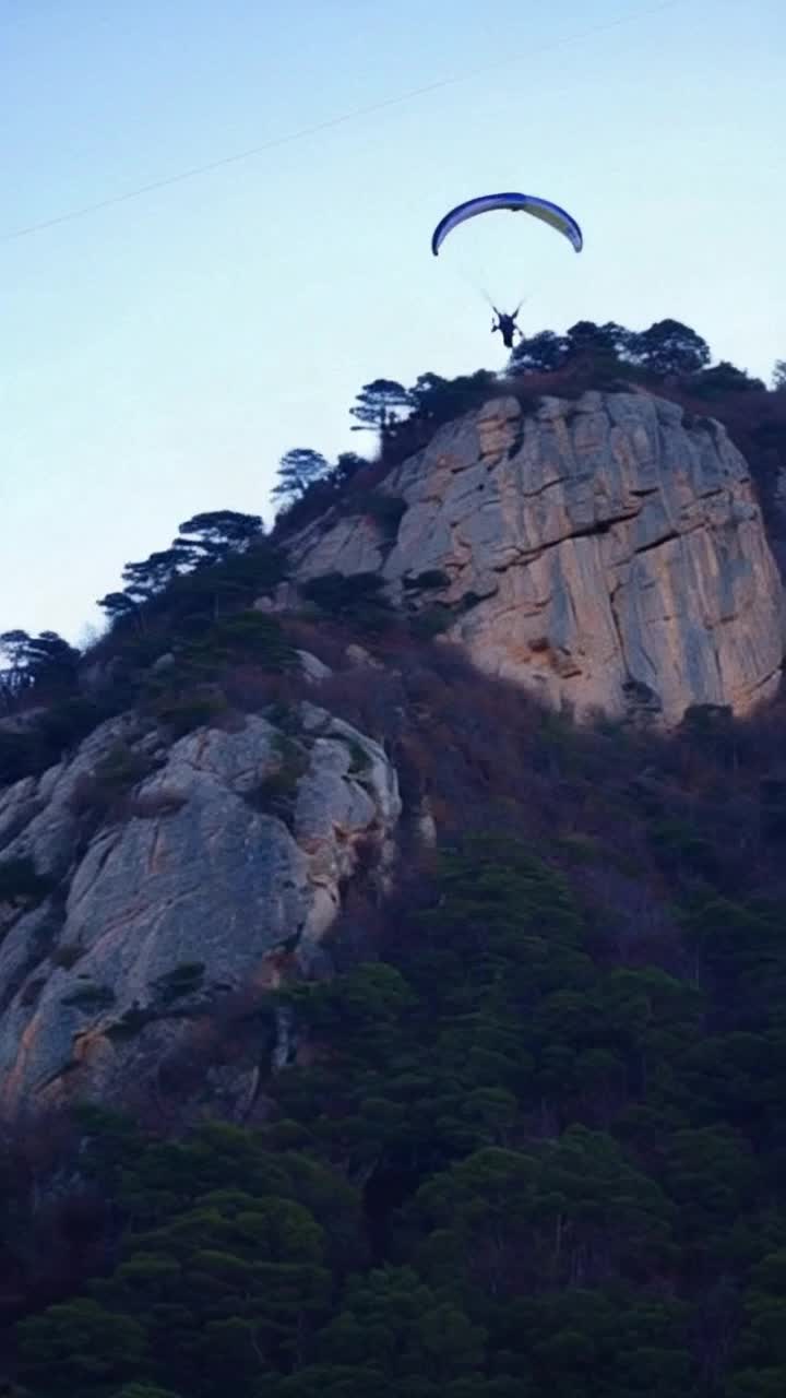 Third person view of a skeleton paragliding down the slope of a rocky mountain closely following the approaching terrain and navigating just enough to avoid any collisions