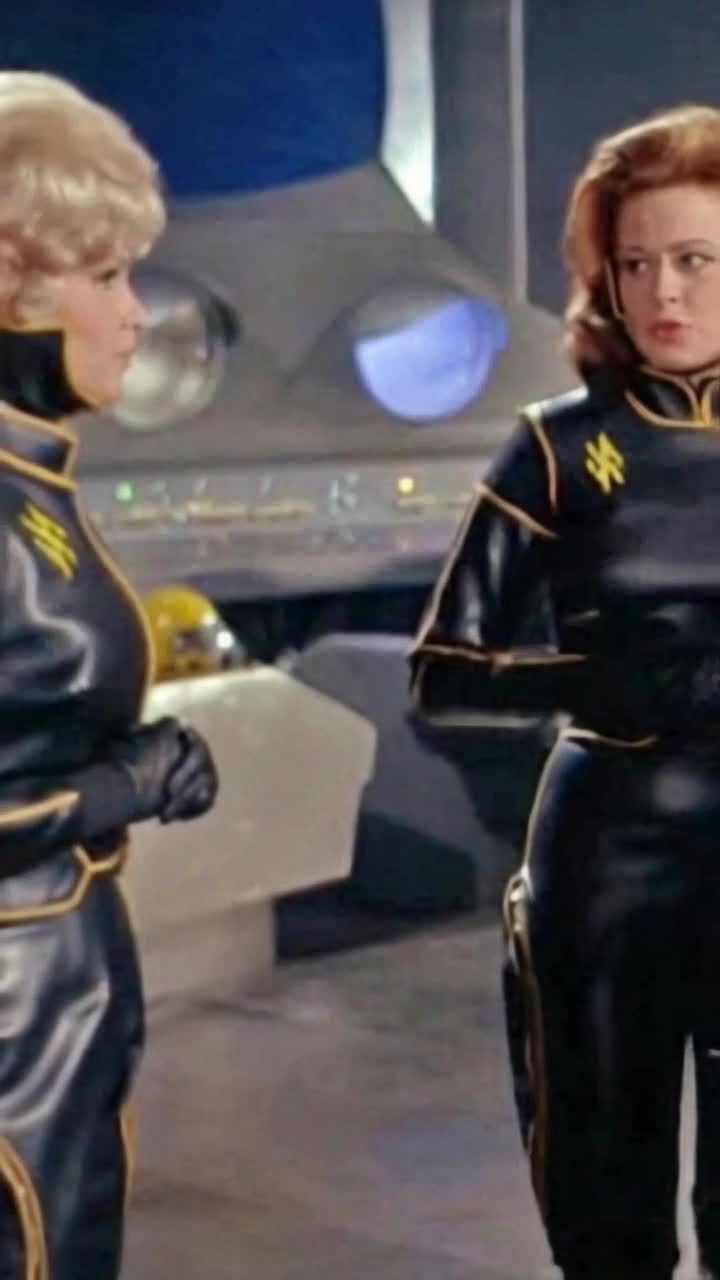 two women move around inside a space ship Both of them walk towards the big computer screen to look at the planet 