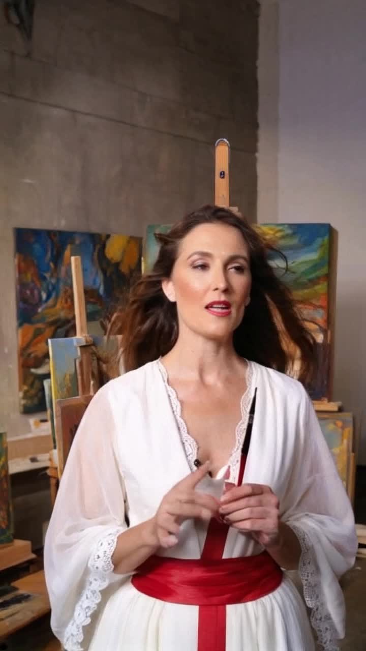 Elegant woman with flowing hair gracefully reciting heartfelt art quotes  Her expressive lips moving passionately capturing the essence of creativity  Serene art studio adorned with vibrant paintings canvases and scattered brushes