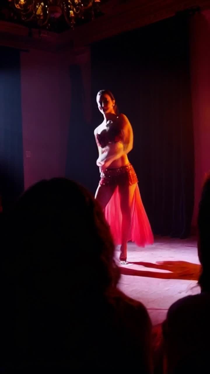  woman gracefully dancing in seminudes captivating audience with each movement Exotic music pulses through the air vibrant colors illuminate dimly lit room shadows play across her alluring silhouette creating an atmosphere of allure and desire