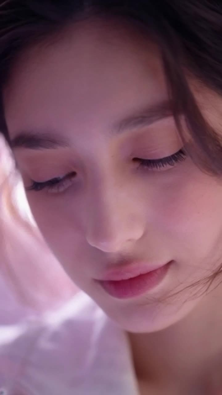 Closeup of a serene face with delicate features and expressive eyes Slow zoom in creating an intimate connection as soft ambient lighting gently highlights contours Subtle hair movement adds lifelike dynamics while a gentle blink brings warmth and personality Blurred background reveals soft pastel colors creating a dreamy atmosphere Throughout the scene maintain a natural realistic look capturing the essence of tranquility Duration 57 seconds
